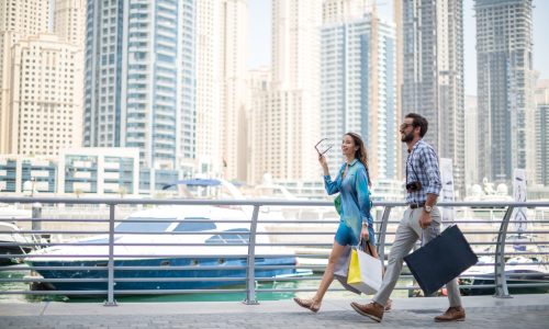 Couple strolling on waterfront carrying shopping bags, Dubai, United Arab Emirates
